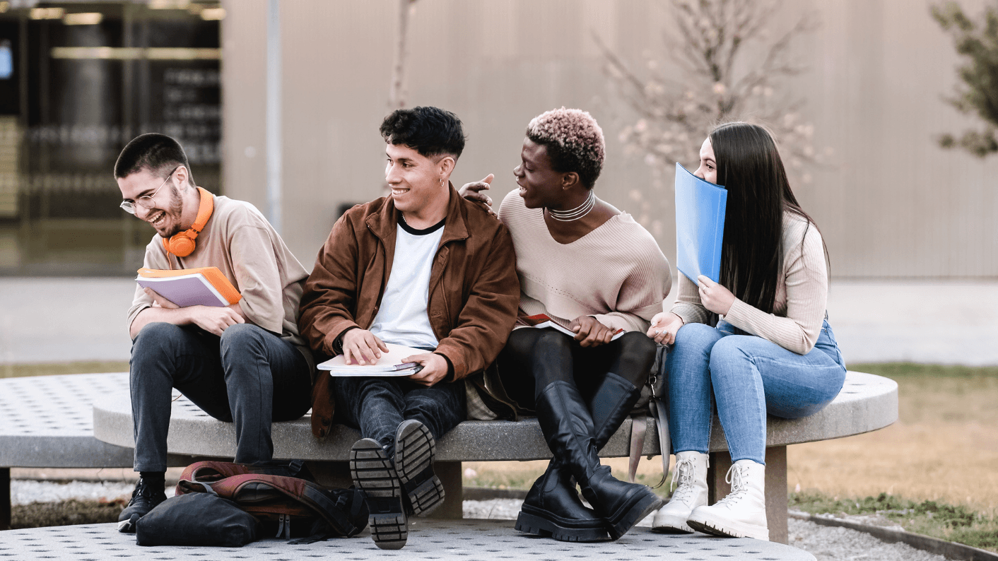 Students on bench laughing and talking.