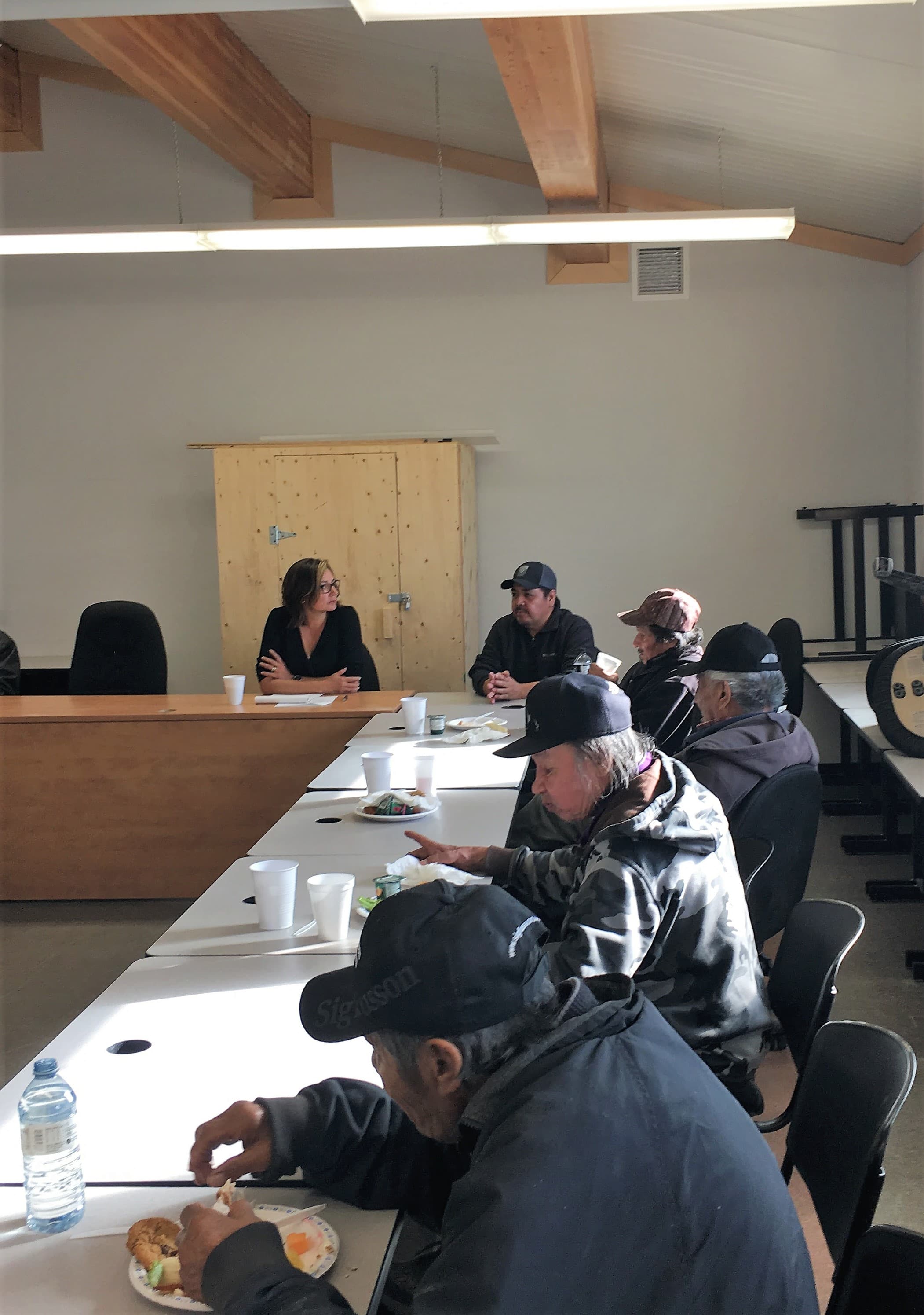 A community discussion with participants seated around tables during a program evaluation session.