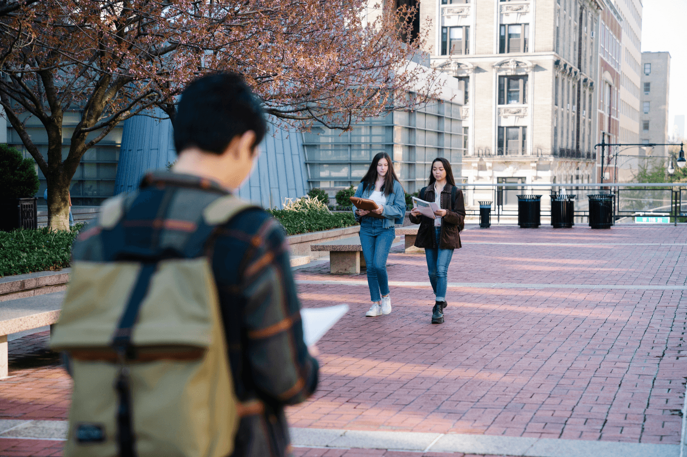 Students walking across a campus courtyard in early spring.