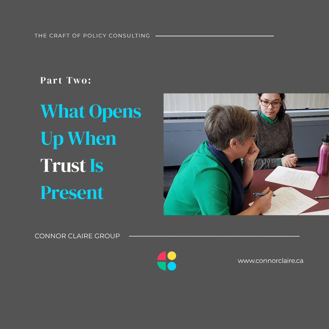 Two people seated at a table in a working session, one leaning in attentively while the other reviews documents, capturing the focused presence of a consulting relationship built on trust.